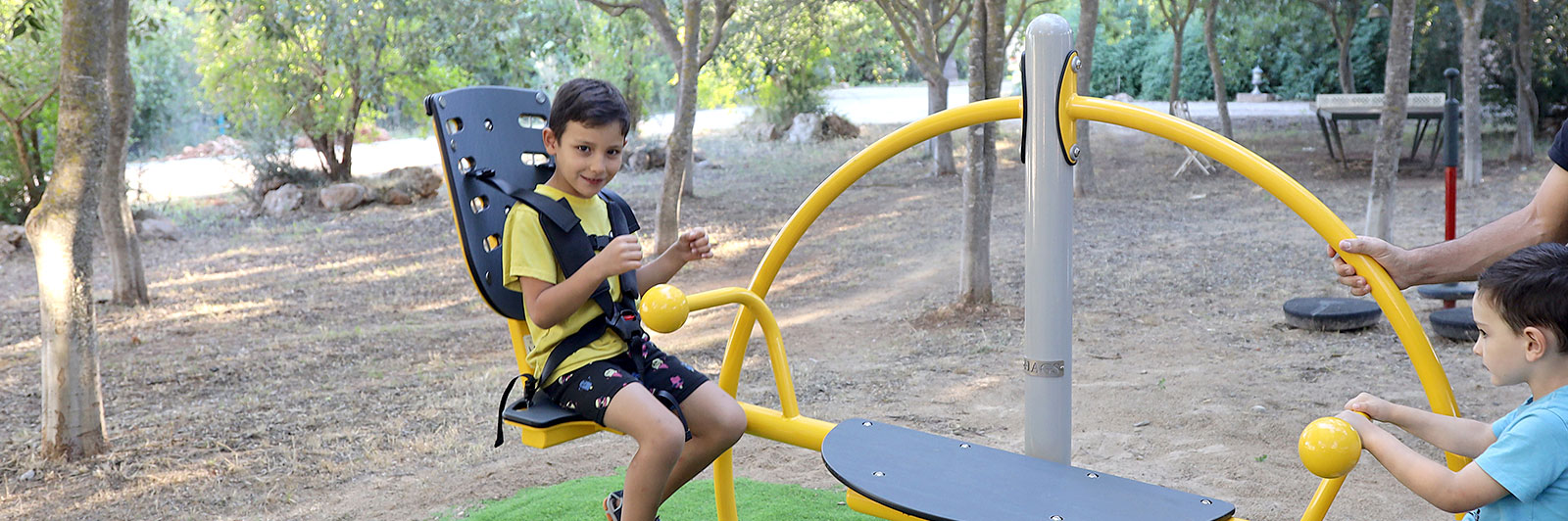 A young boy is strapped in on an inclusive seesaw seat.